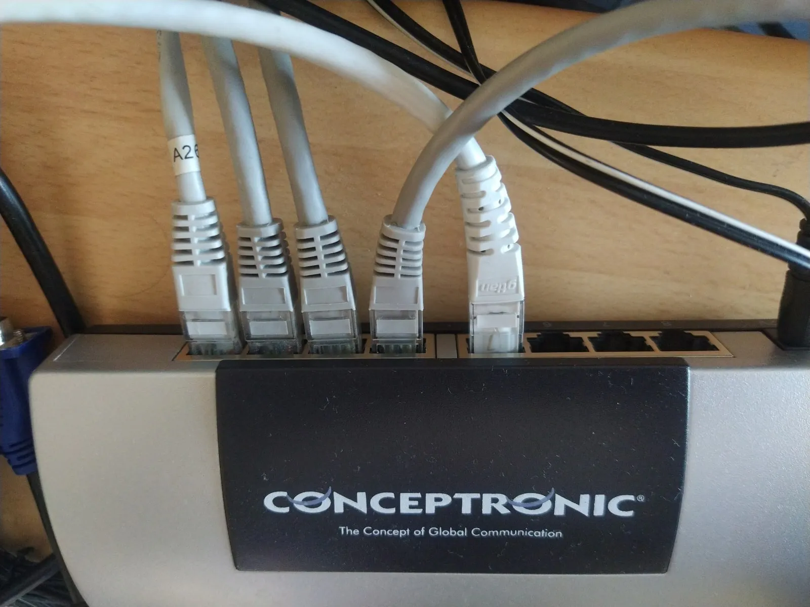 An eight-port desktop Ethernet switch with five grey patch cables plugged into its ports and three ports empty.