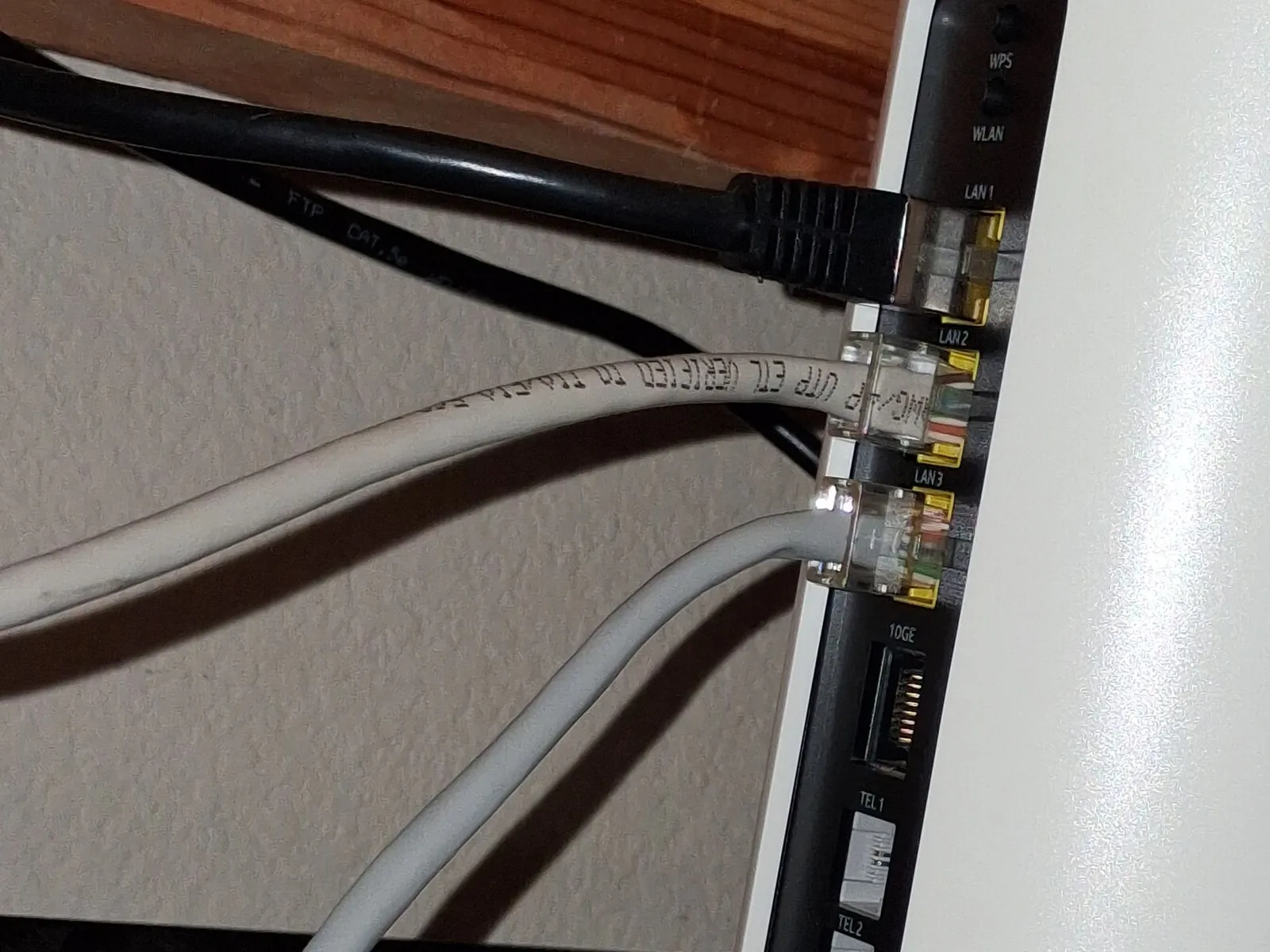 Ethernet cables plugged into three yellow ports on the back of a white gateway, with an empty port labelled 10GE below them.
