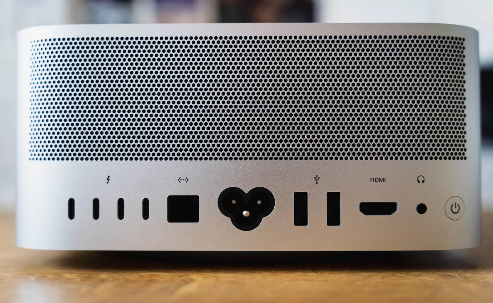 The silver back panel of a Mac Studio below its perforated vent: four Thunderbolt ports, an Ethernet jack, the power inlet, two USB-A ports, HDMI, a headphone jack and the power button.